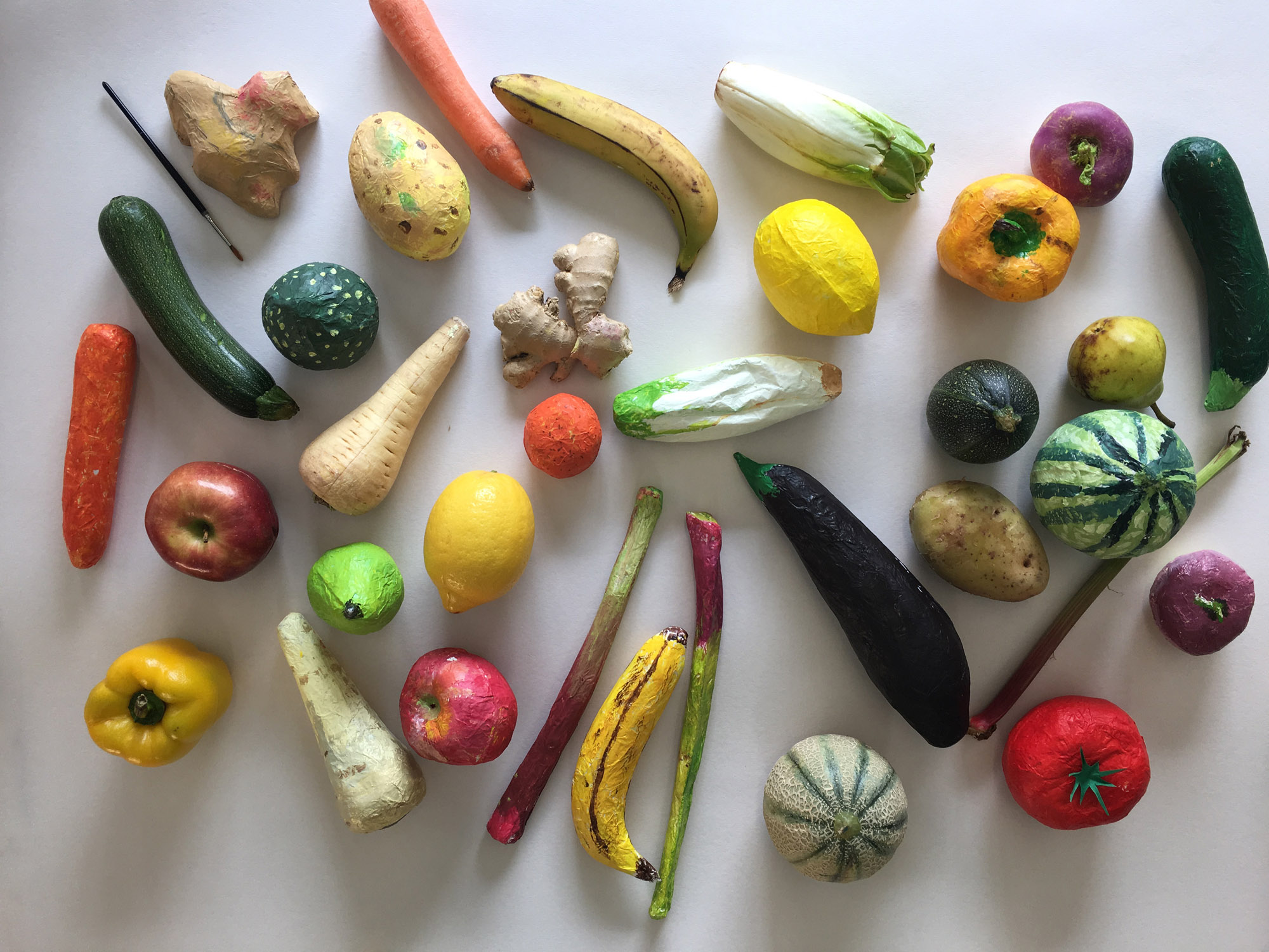 Ensemble de fruits et légumes vus sur fond blanc : vrais légumes et reproductions en papier
