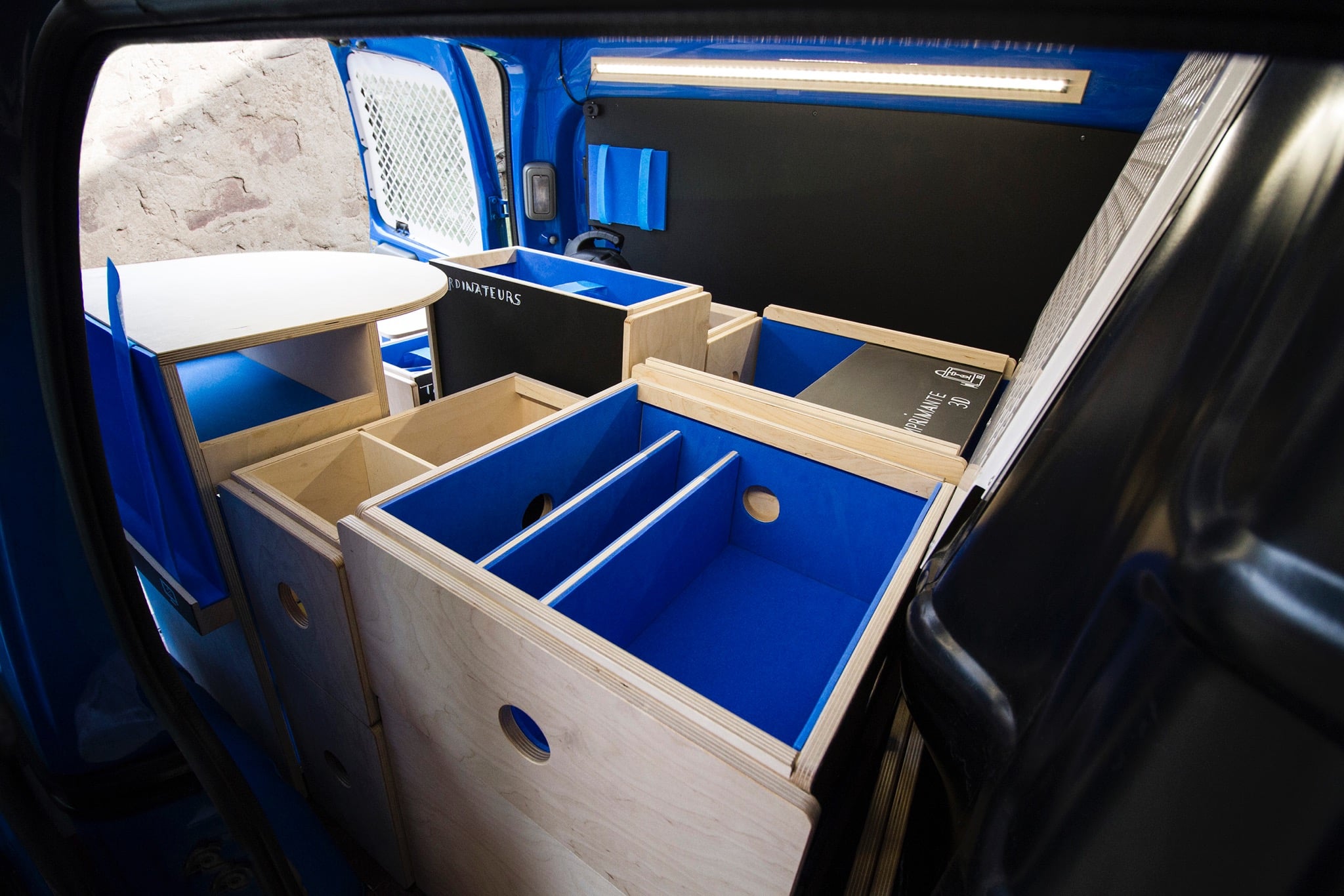Vue depuis l'intérieur du véhicule bleu, noir et bois, avec aperçu des caisses de rangement en bois molletonnées
