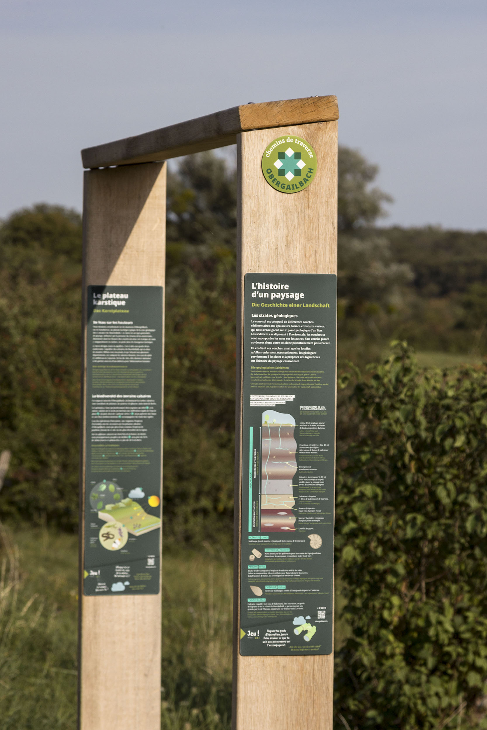 Banc bois de la collection Demi-Lieue, sous forme de cadre sur le paysage, avec deux panonceaux documentaires illustrés : "L'histoire d'un paysage" et "Le plateau karstique".