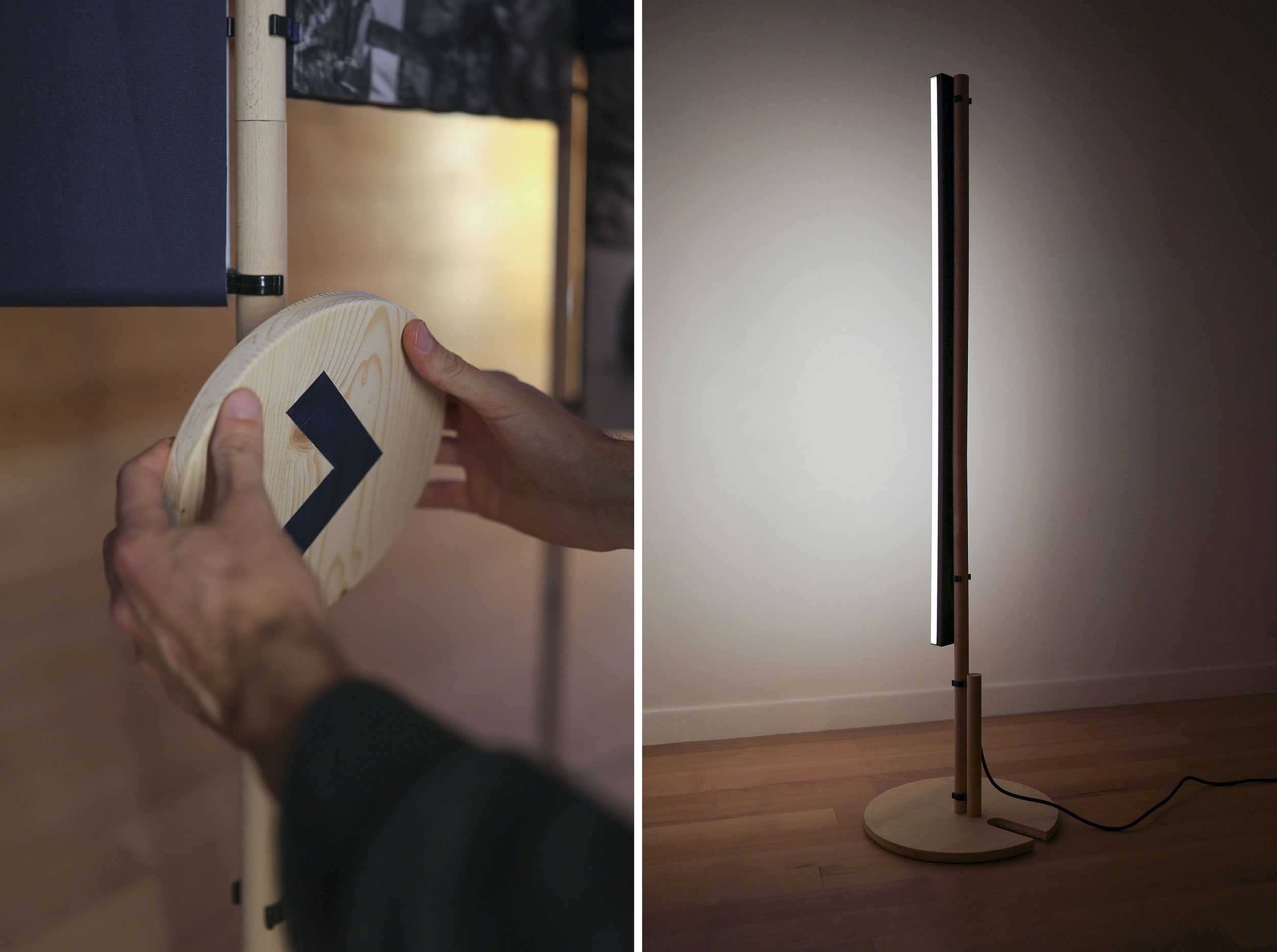 A gauche, on voit une main en train de fixer un disque imprimé d'une flèche, sur le montant scénographique. A droite, on voit une lampe longiligne, fine, sur pied, allumée.