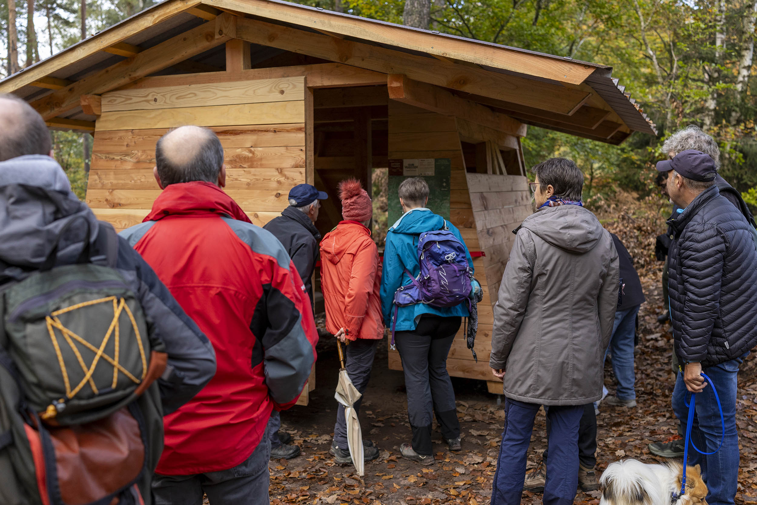 De nombreux randonneurs se pressent pour découvrir et visiter le nouvel abri forestier. Ils observent la cartographie, d'autres patientent pour y entrer.