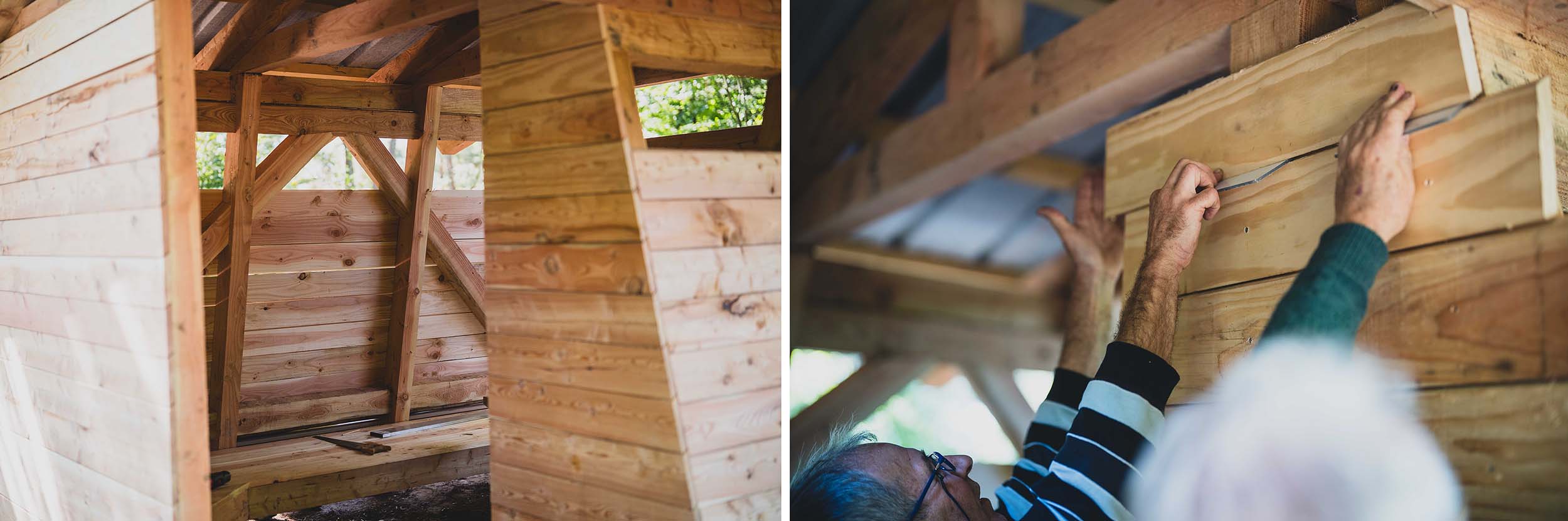 Pose du bardage avec une cale pour gérer l'espacement de chaque lame de bois de douglas. On voit à gauche l'intérieur de l'abri, fini, et à droite deux personnes qui sont en train de régler le positionnement de la dernière planche.